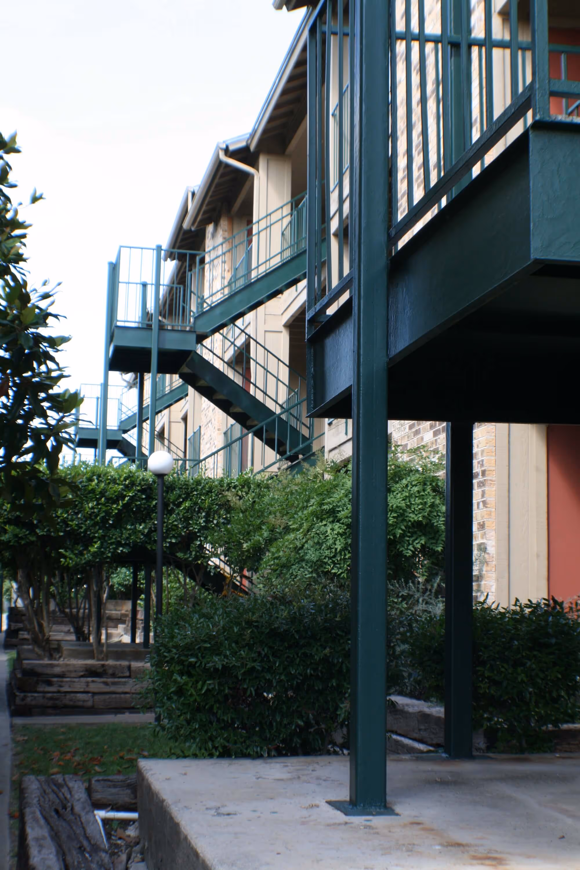 Stadium View Apartments outdoor entrances and stairs to unit, surrounded by trees and bushes.