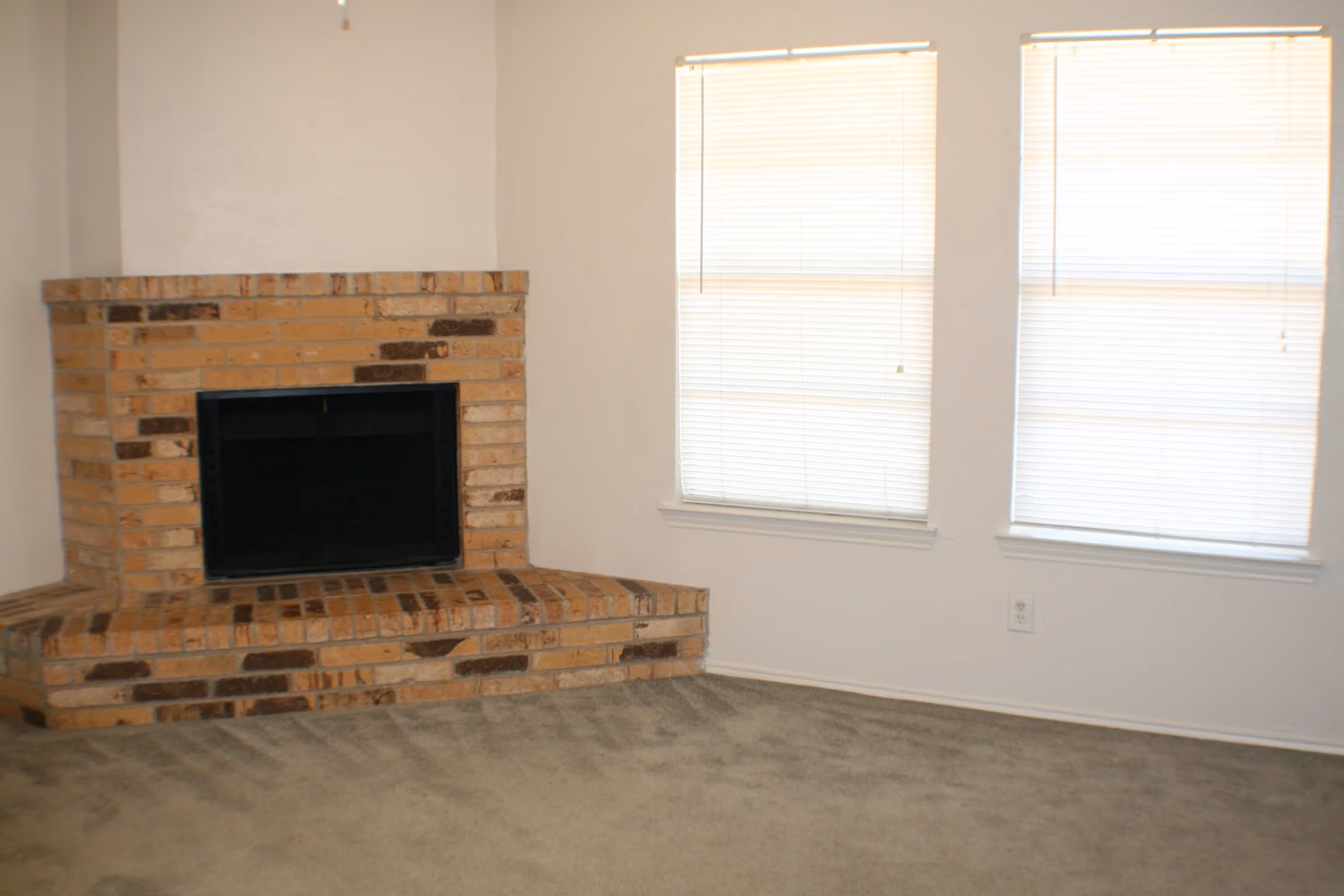 A living room featuring a brick fireplace at Stadium View Apartments.
